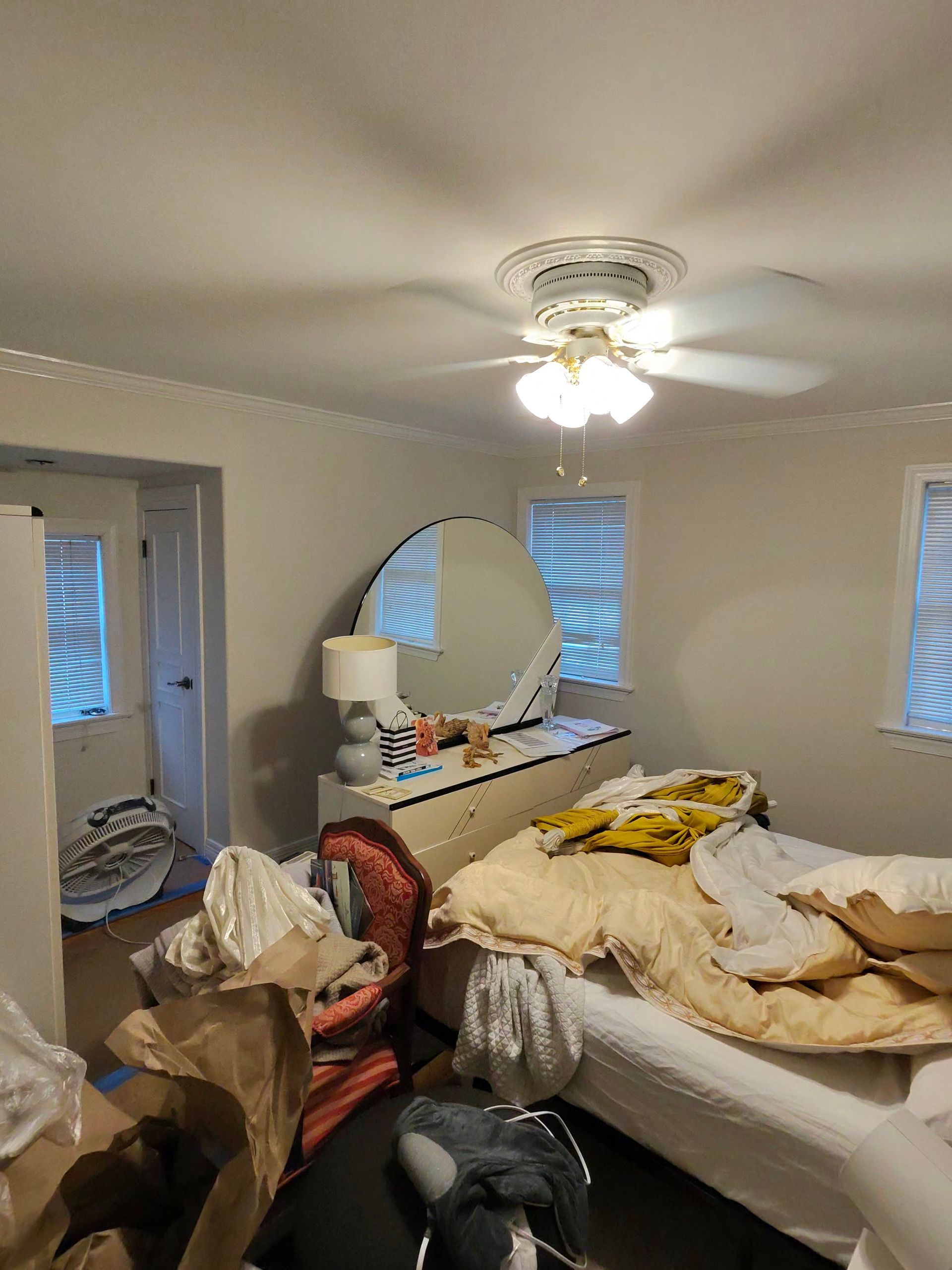 Person wearing gloves smoothing drywall compound onto a wall with a trowel.