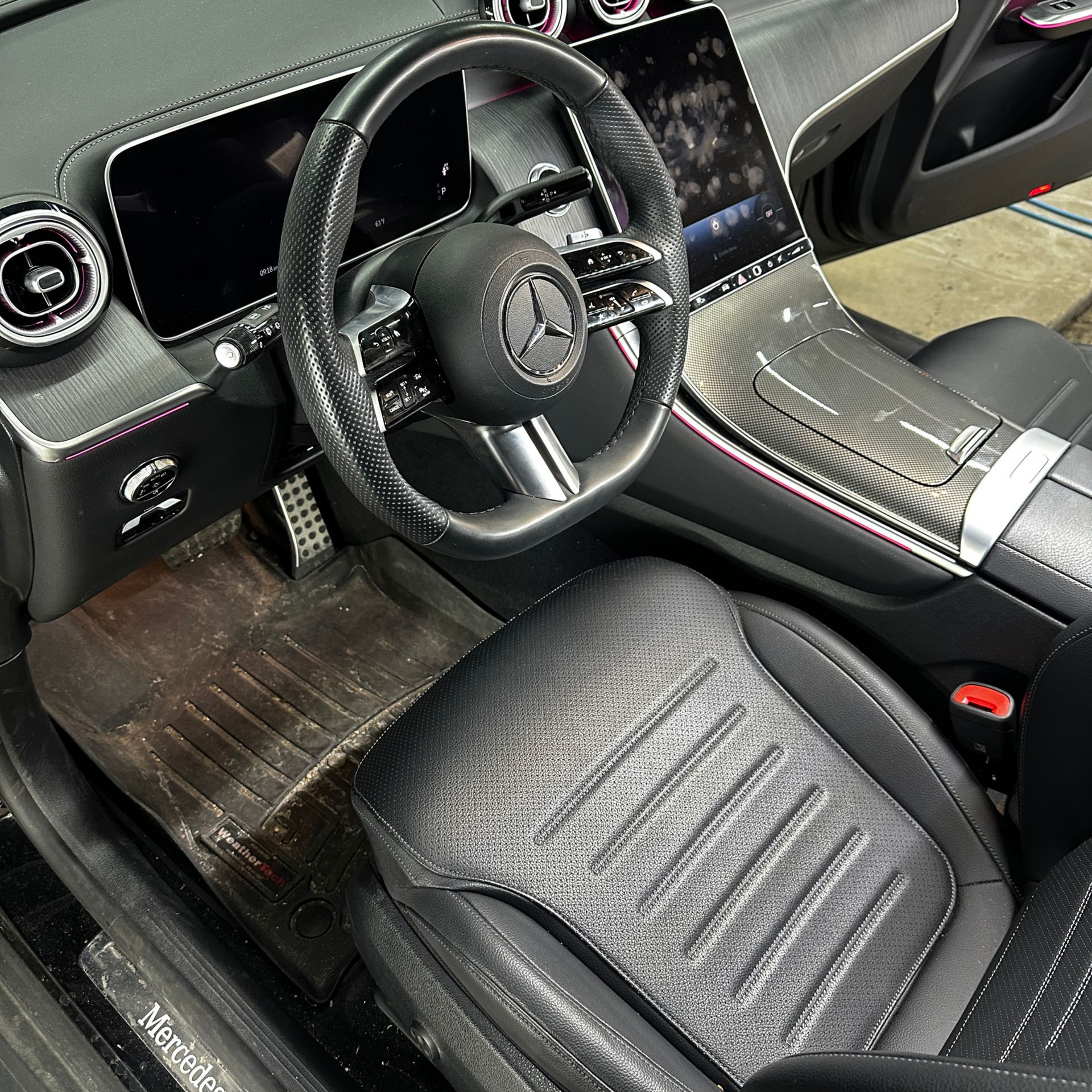 Interior of a Mercedes-Benz car with wet leather seats and flooring covered in droplets from rain.