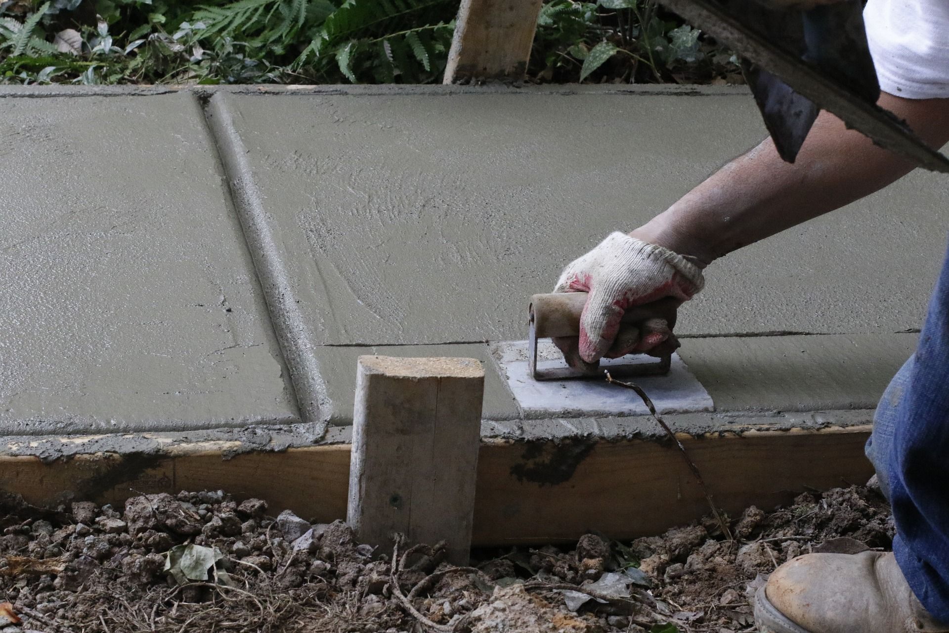 a concrete worker finishing a concrete sidewalk