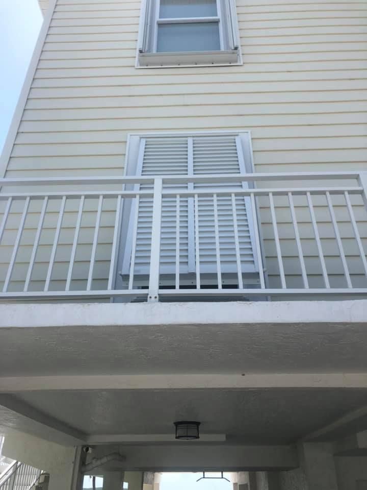 A close up of a black metal fence with a palm tree in the background.