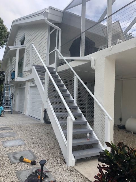 A man wearing a welding mask is welding a metal railing.