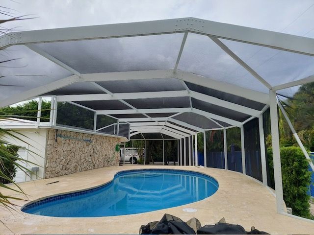 A patio with a pergola, tables, chairs and a grill.