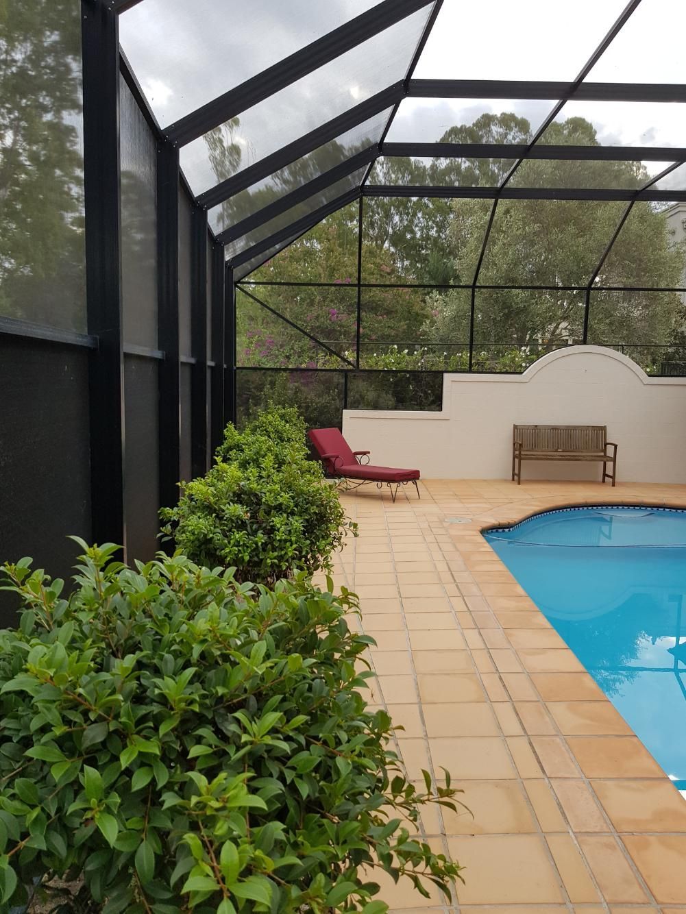 A screened-in area with a swimming pool and a bench.