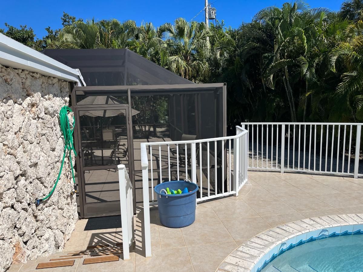 A screened in area next to a swimming pool.