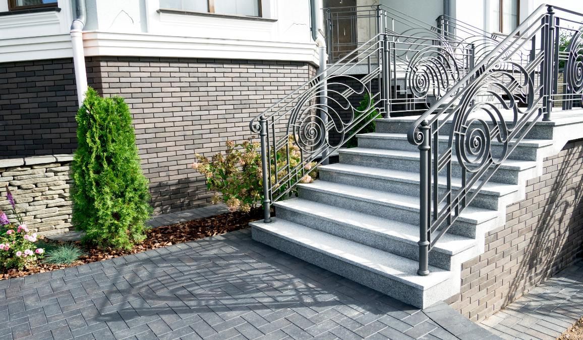 A set of stairs leading up to a house with a wrought iron railing.