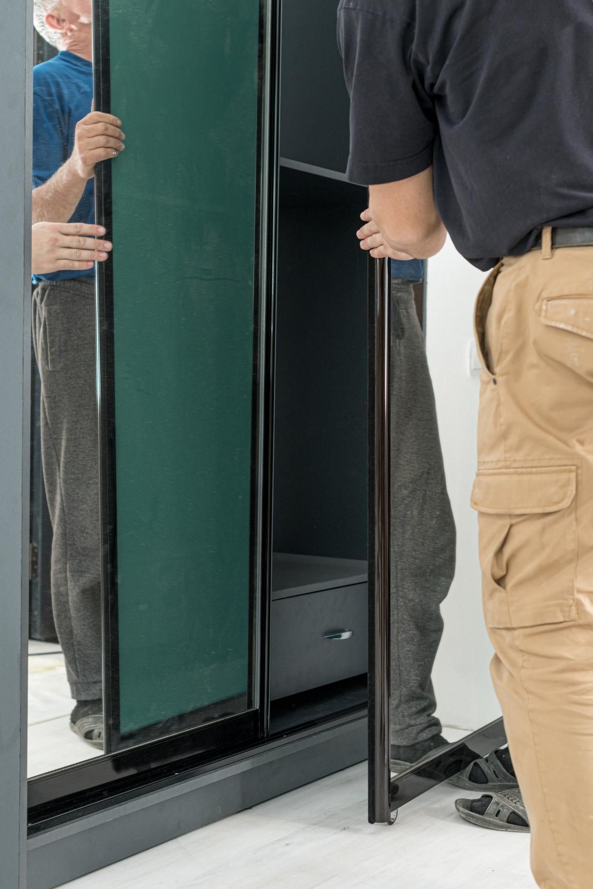 A man is opening a sliding glass door of a safe.