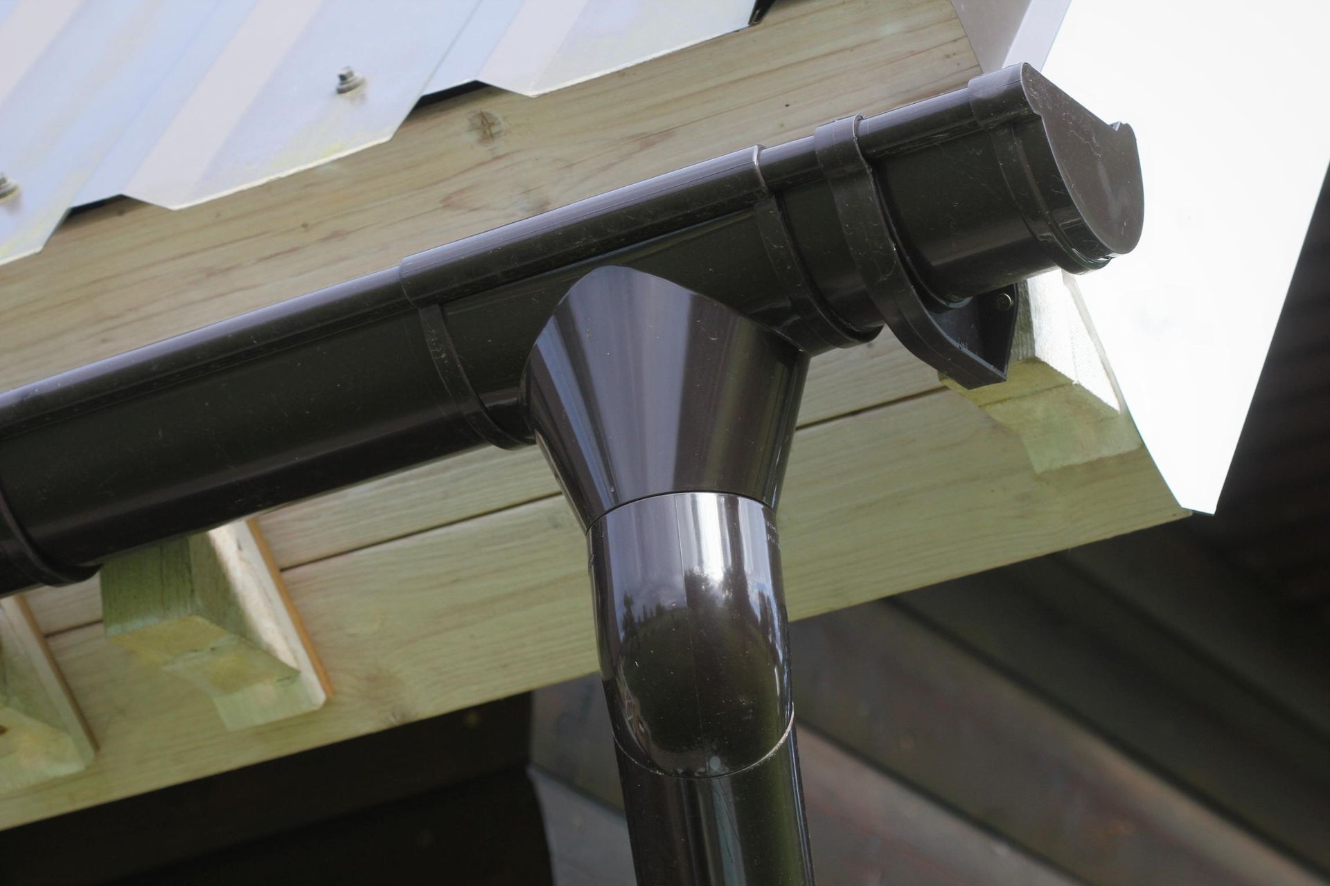 A close up of a black gutter on a wooden roof.