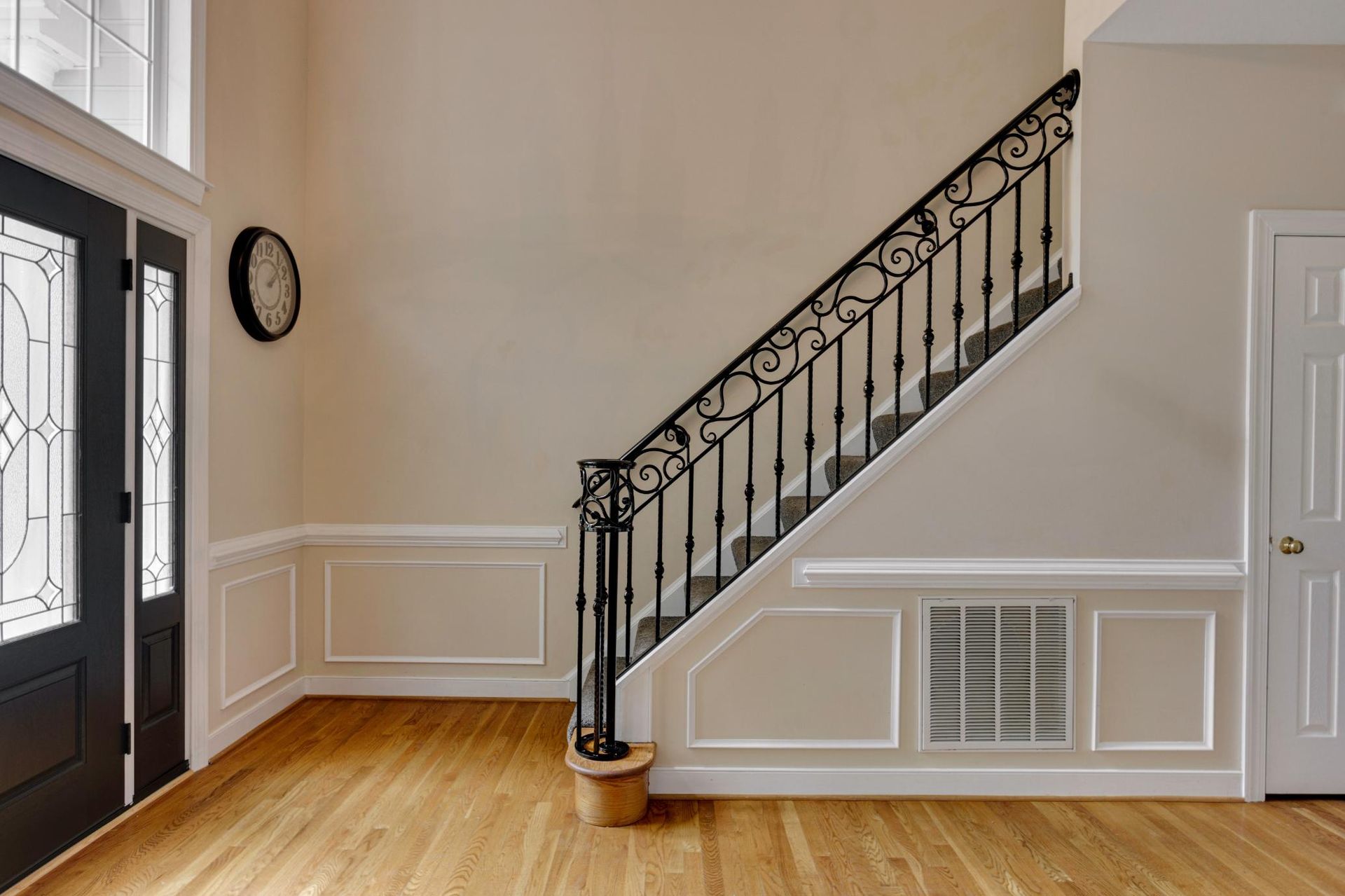 An empty hallway with a staircase and a clock on the wall.