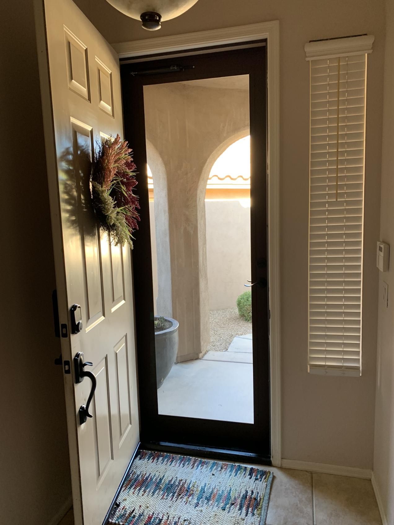 A door with a wreath on it and a rug in front of it