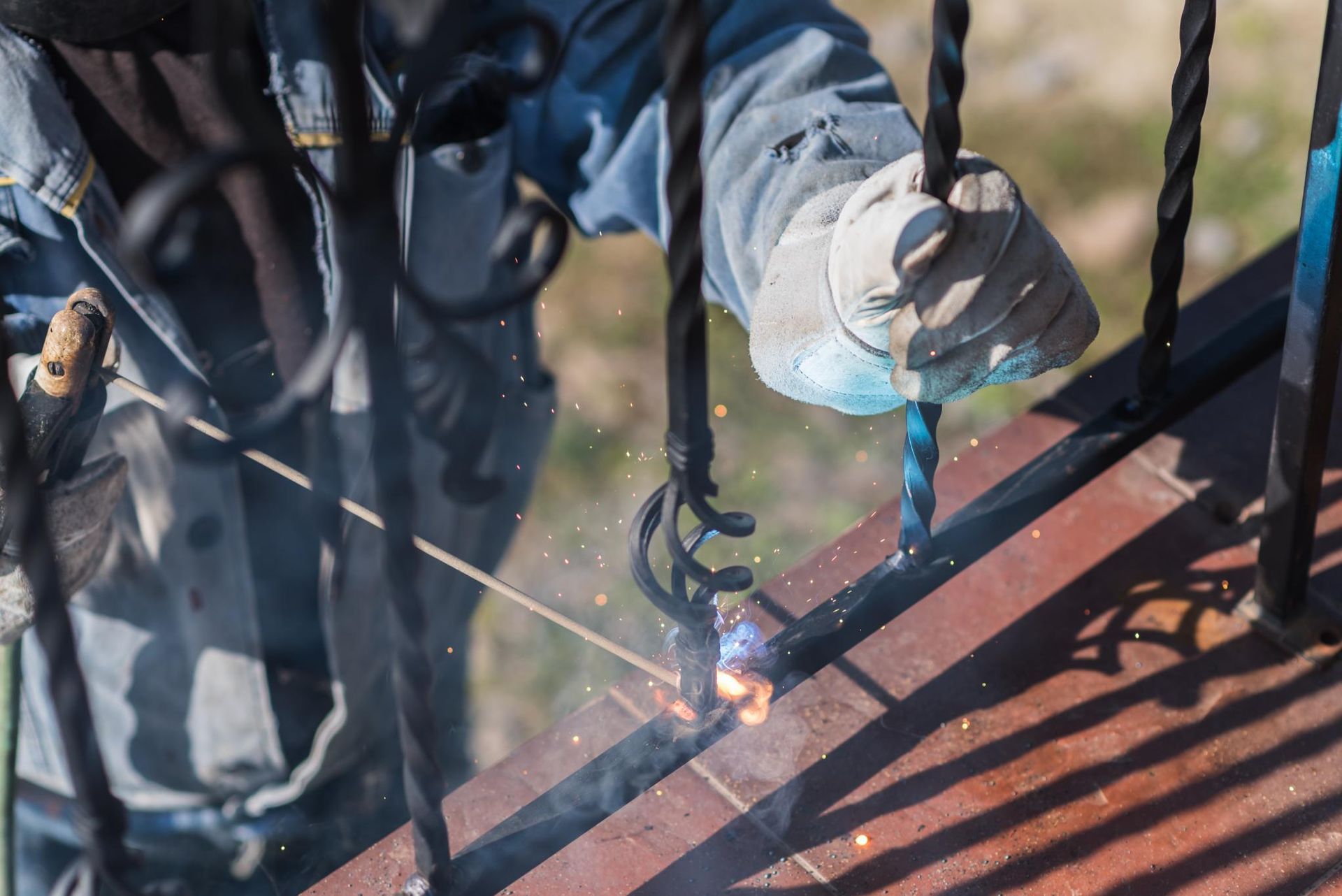 A man is welding a metal railing on a balcony.