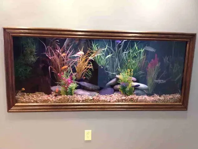 A large fish tank is hanging on a wall in a room.