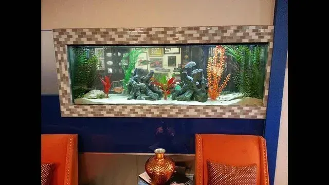 A large fish tank is hanging on the wall in a living room.
