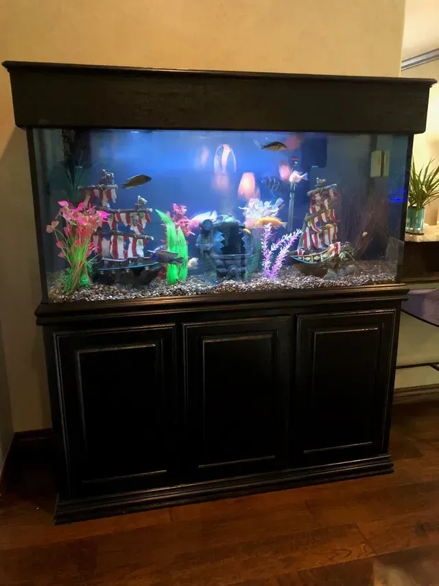 A large fish tank is sitting on top of a wooden cabinet in a living room.