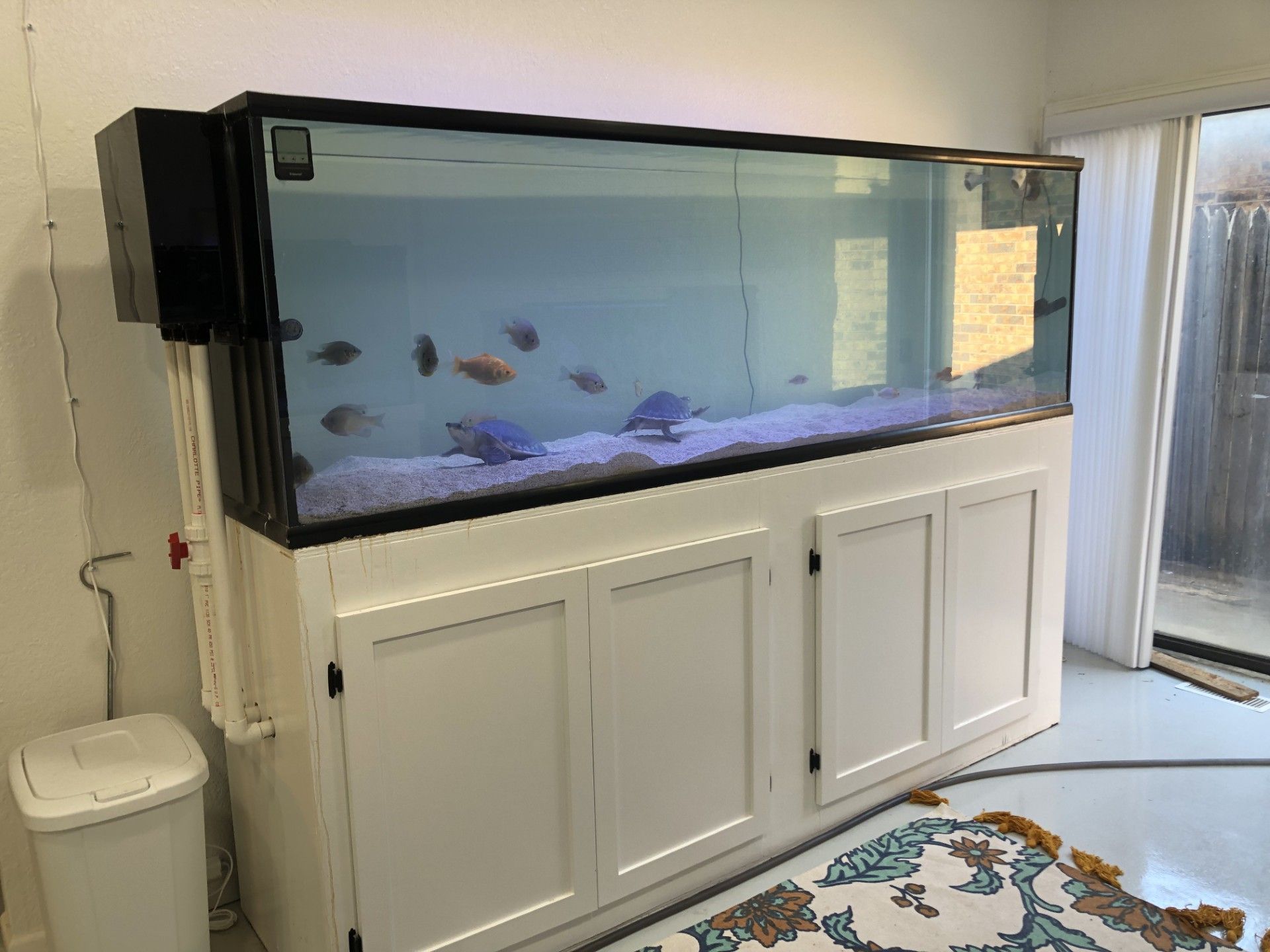 A large fish tank is sitting on top of a white cabinet in a room.