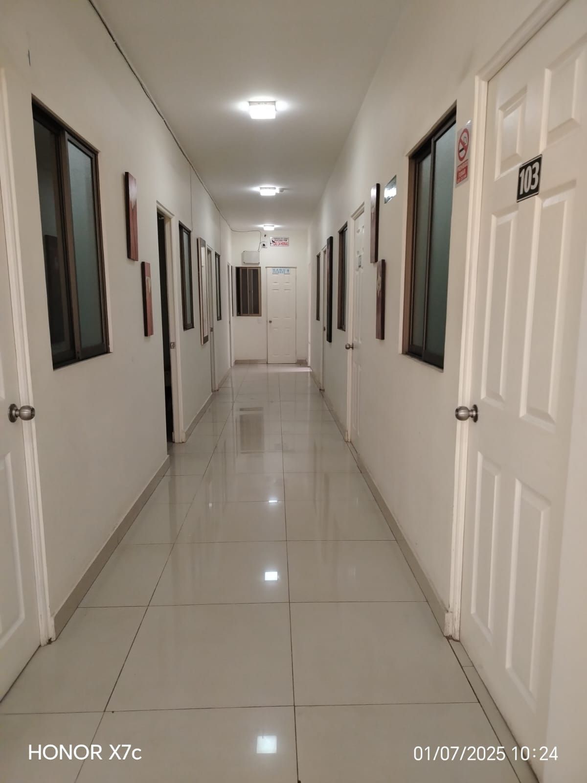 Un largo pasillo con muchas puertas y ventanas.