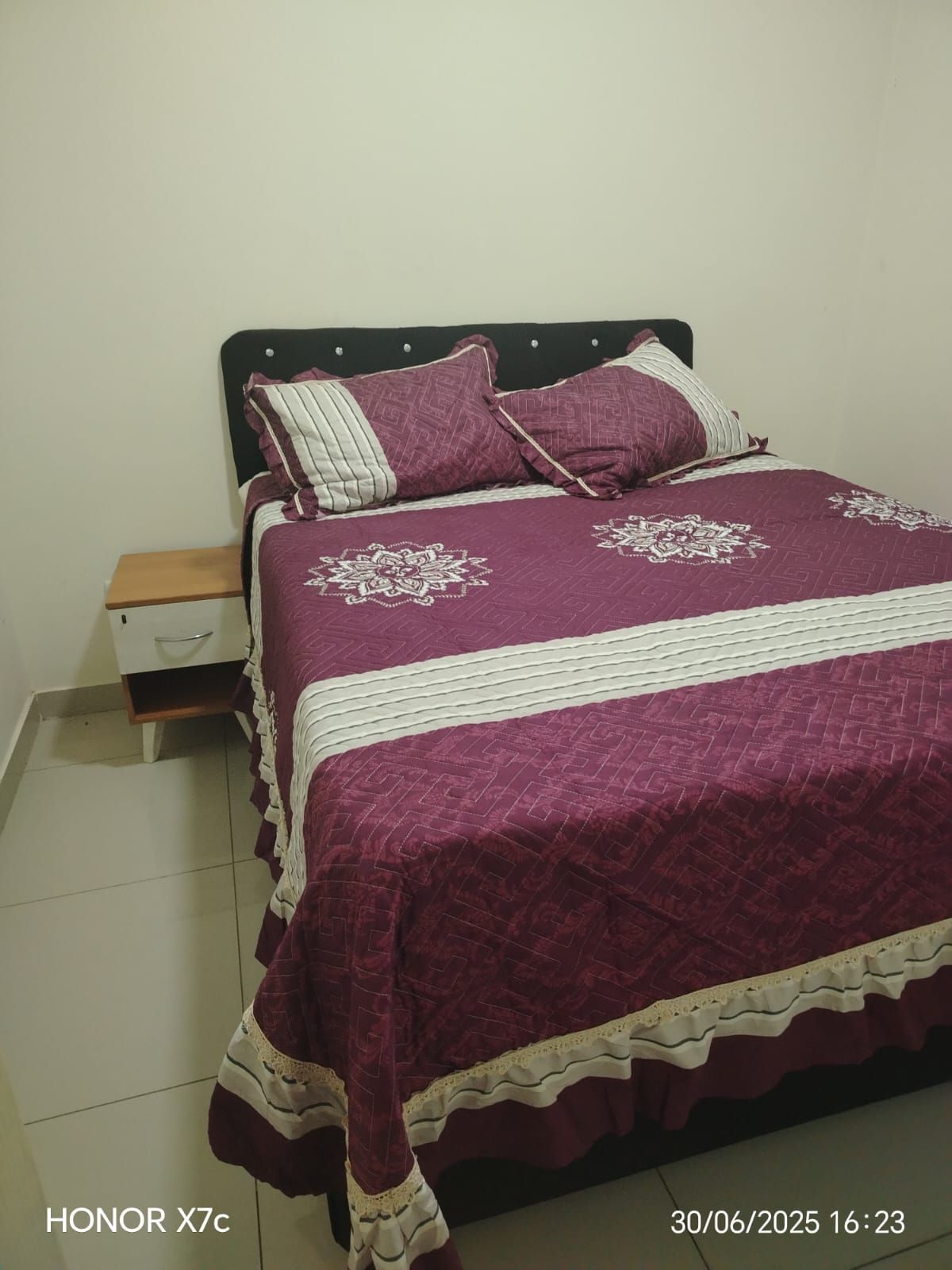 Una cama con un edredón y almohadas de color morado en un dormitorio.