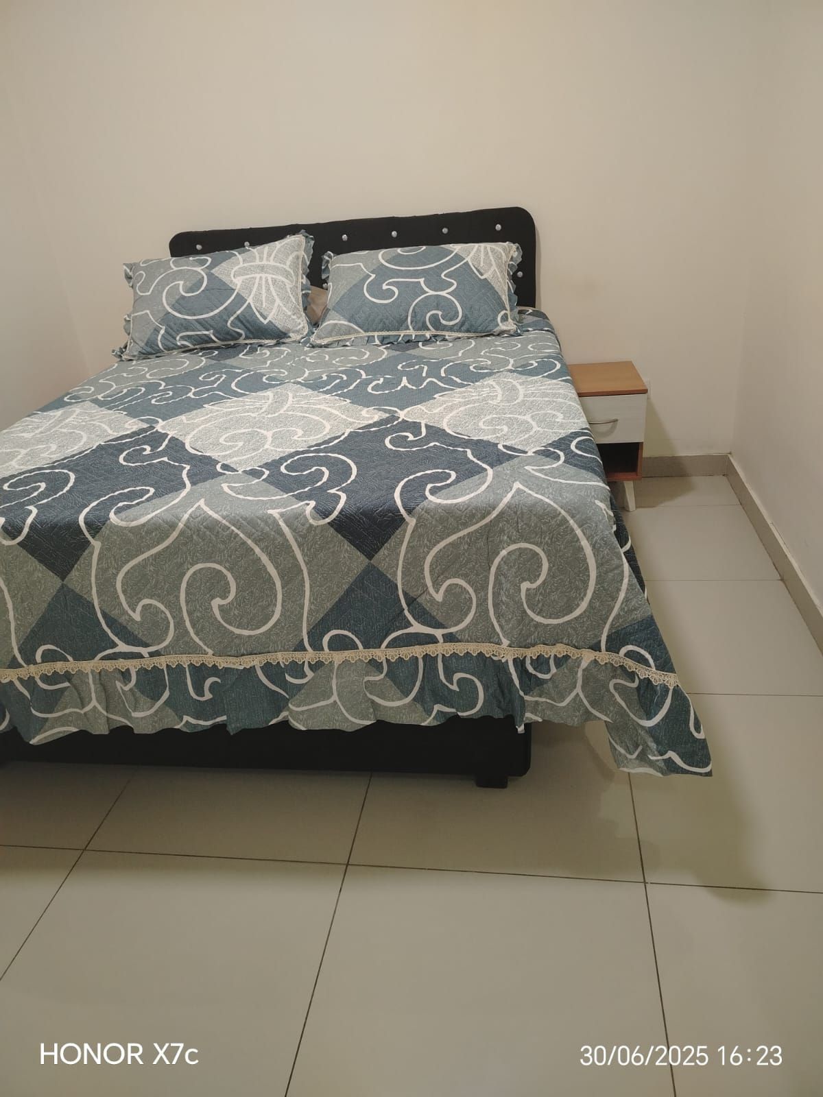 Una cama con un edredón a cuadros y almohadas en un dormitorio.