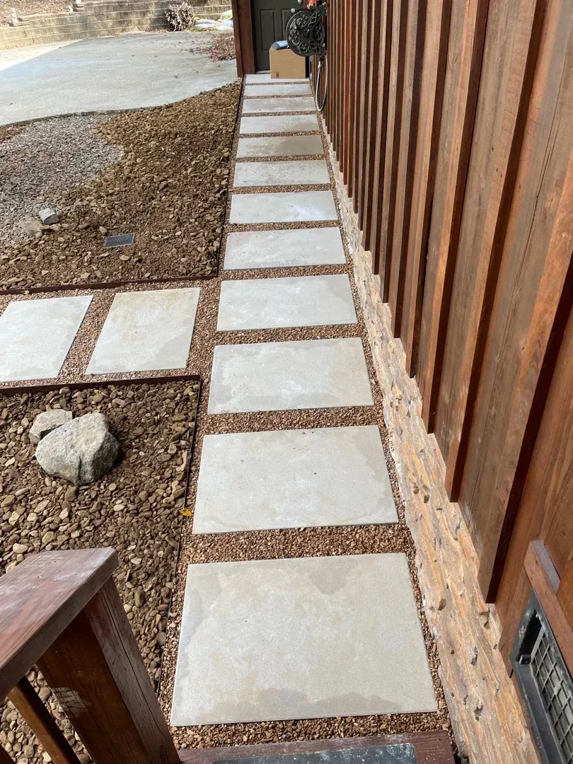Stone pathway bordered with gravel along a wood-paneled building.