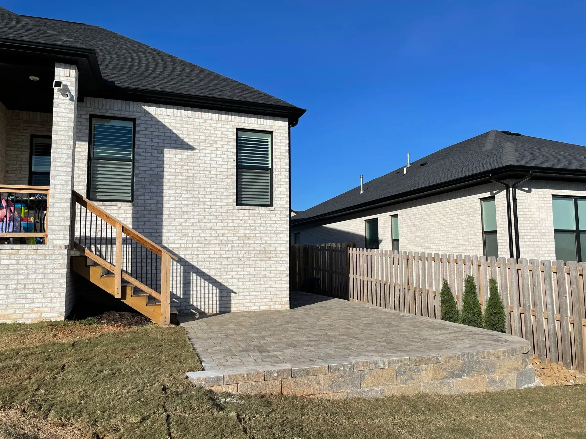Brick house with a patio and wooden fence on a sunny day.
