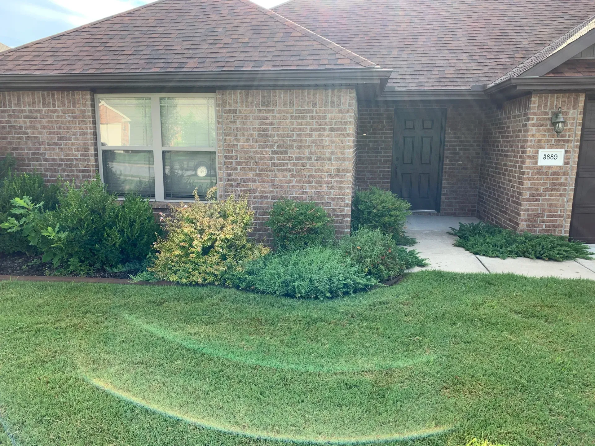 Brick house with green lawn and bushes. Doorway, window, and address 2b are visible.