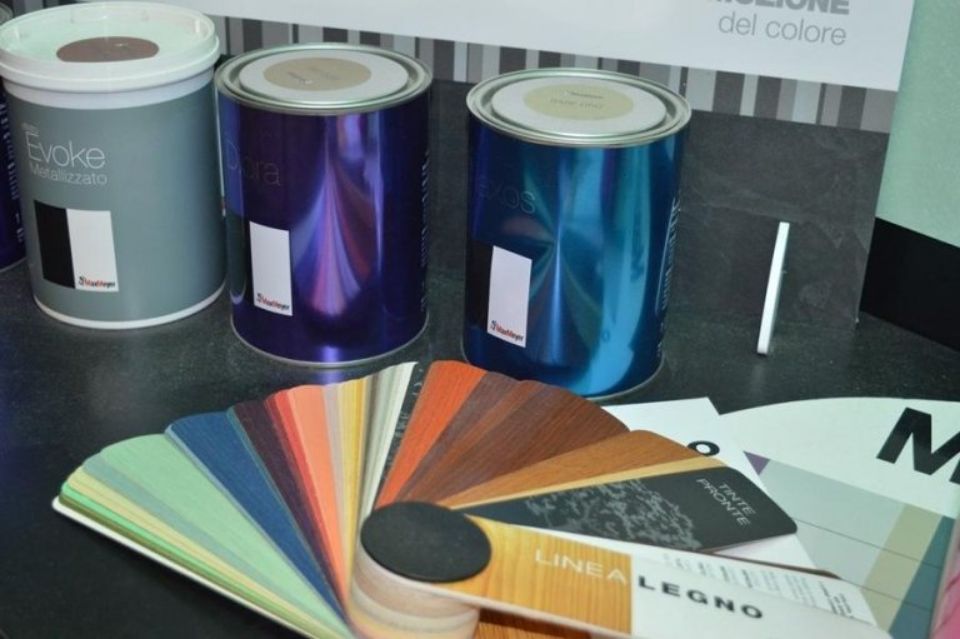 diversi barattoli di vernice sono seduti su un tavolo accanto a un ventaglio di colori