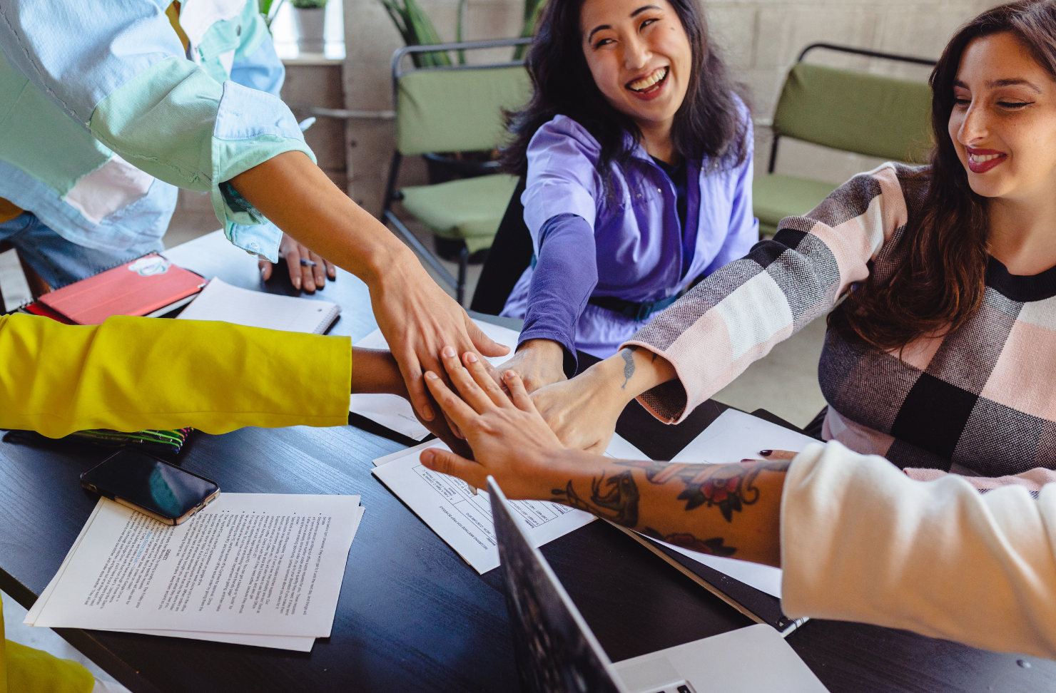 A group of people are putting their hands together at a table.