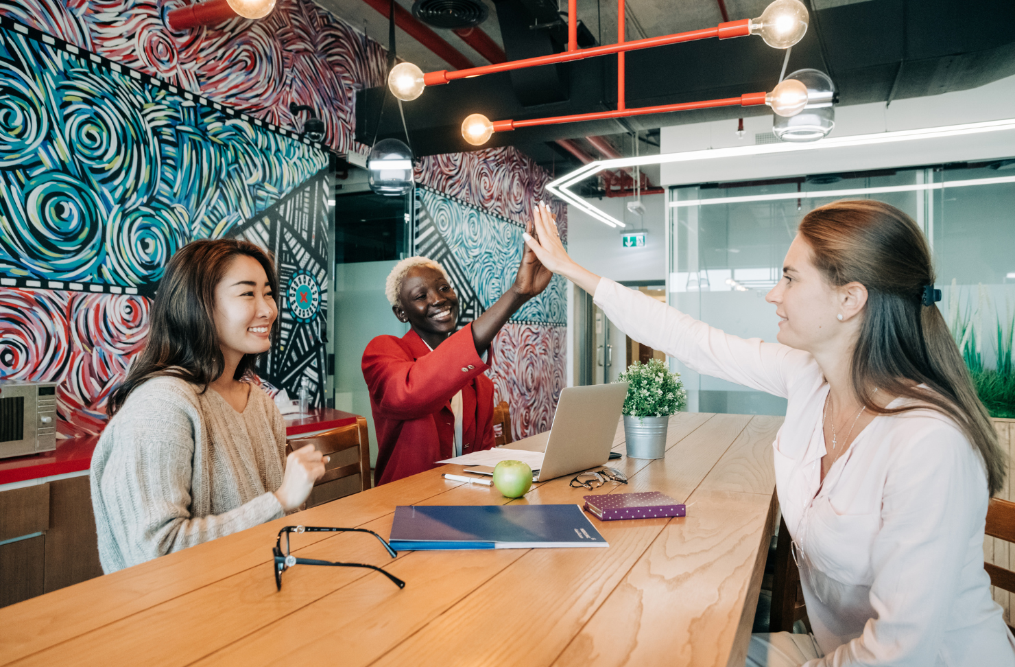 A group of people are giving each other a high five while sitting at a table.