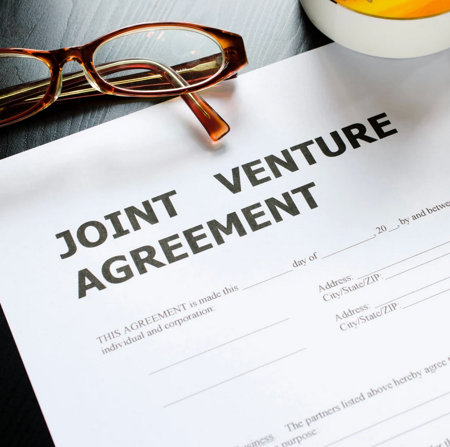 A joint venture agreement is on a table next to a pair of glasses