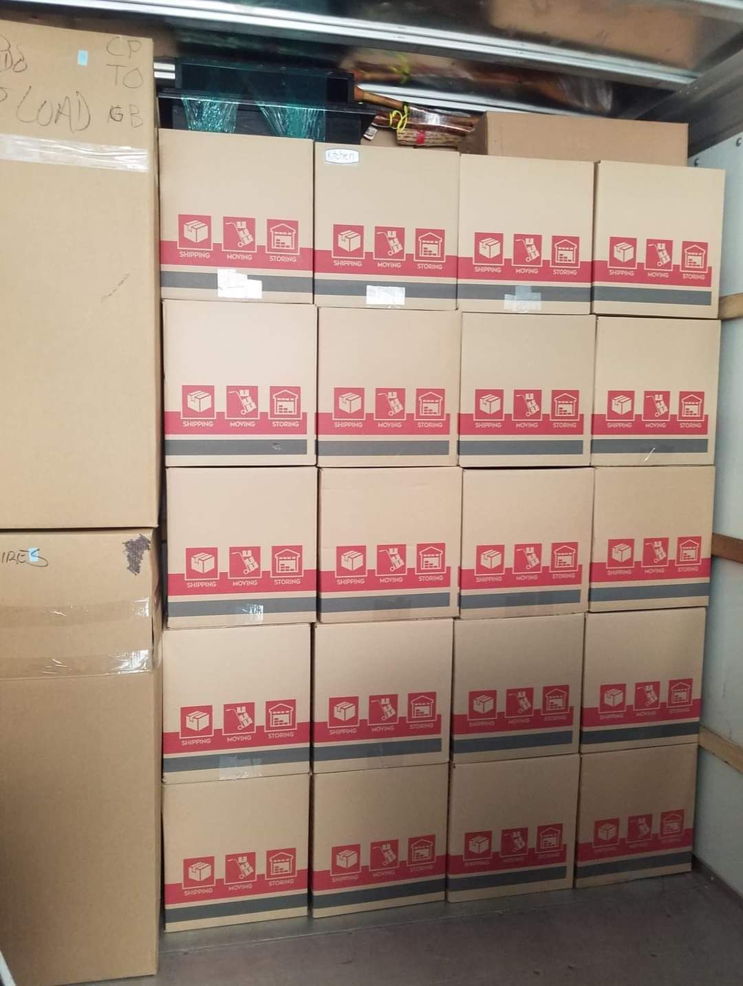 Stacks of beige cardboard boxes with red labels neatly piled in a storage area.