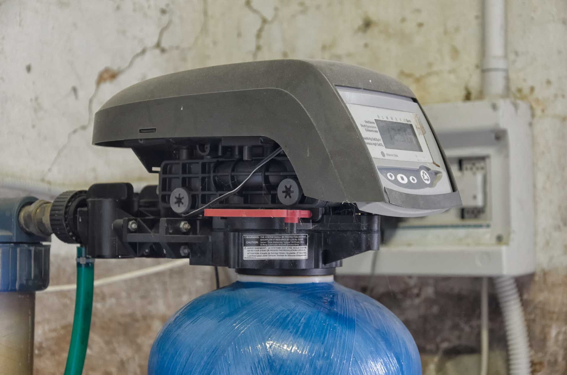 A water softener is sitting on top of a blue tank.