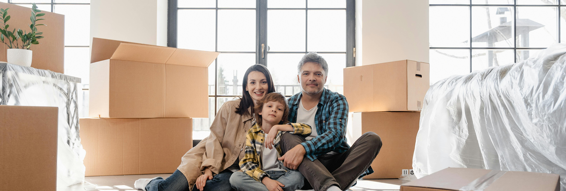 Family sits in a new home, surrounded by moving boxes.