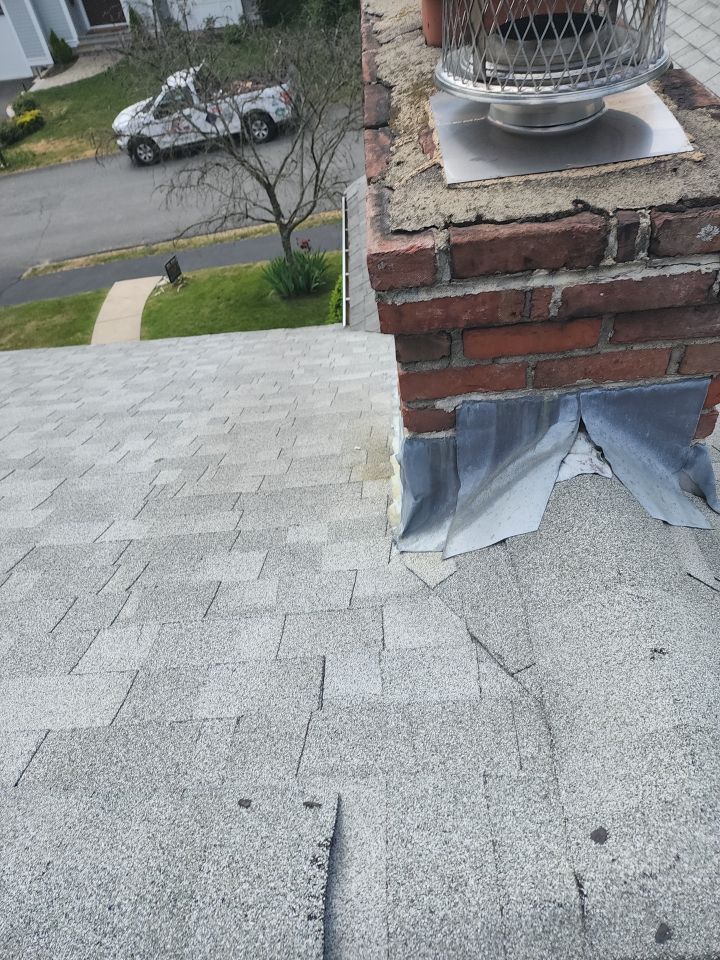 A roof with a chimney on top of it and a truck parked in the background.