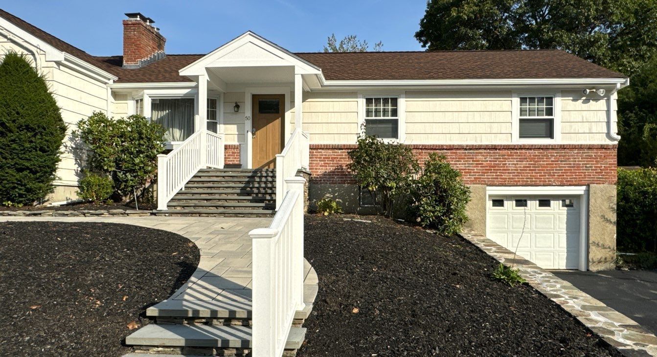 The front of a house with a white fence and stairs leading up to it.