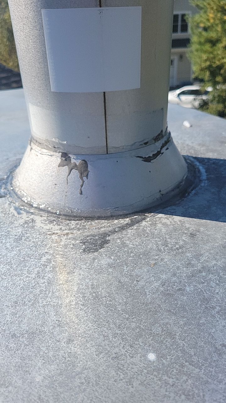 A close up of a metal pipe on a roof with a sticker on it.