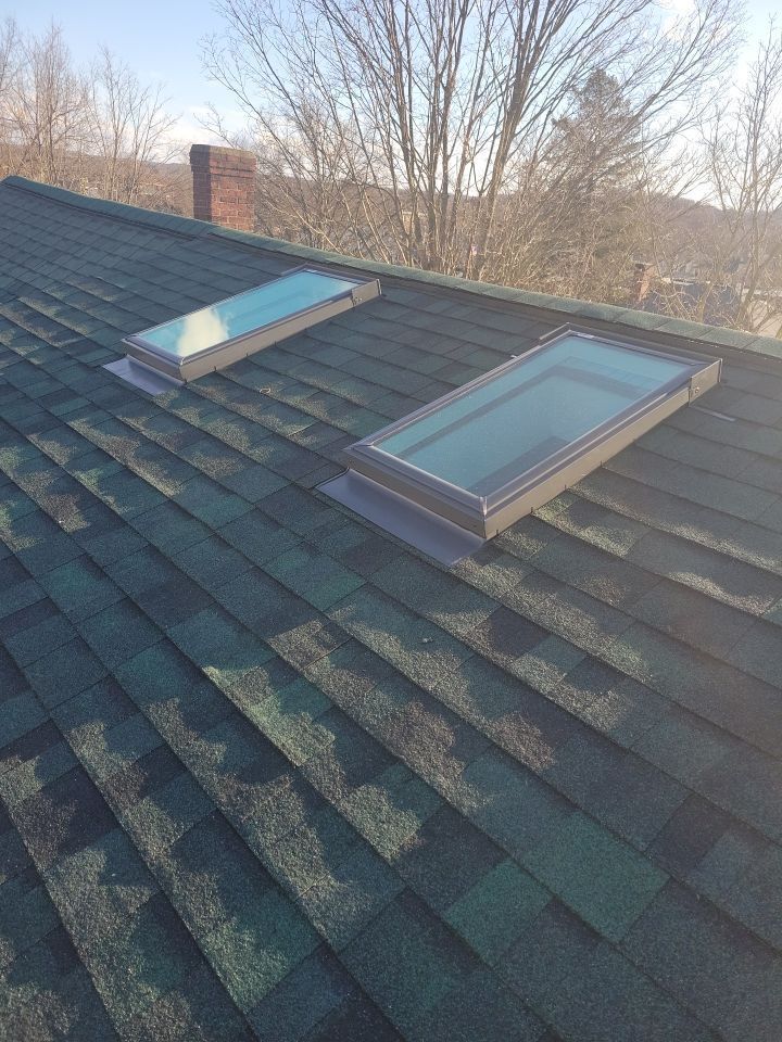 There are two skylights on the roof of a house.