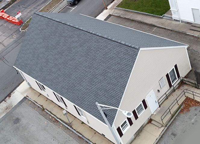 An aerial view of Milford Food Pantry with a brown roof and surrounding parking lot and streets.