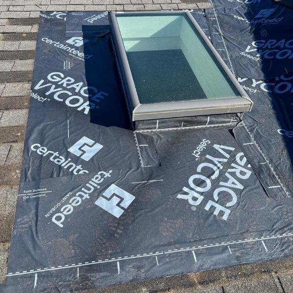 Skylight on a shingle roof with black roofing underlayment.