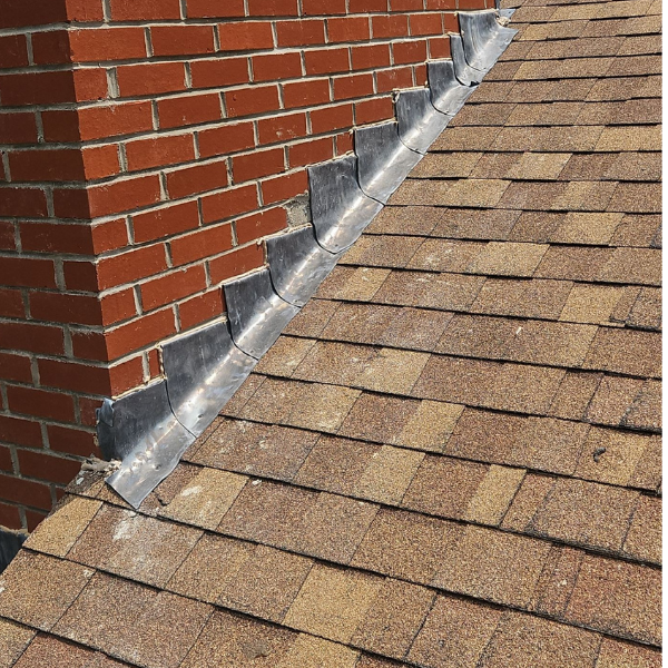Patched and deteriorated chimney flashing before a roof replacement in Grafton, MA.