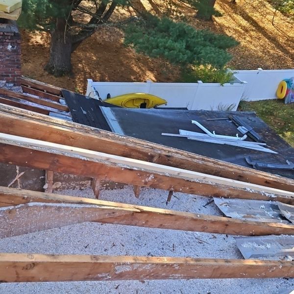 A roof in disrepair with exposed wooden beams, debris, and a yellow kayak in the background.