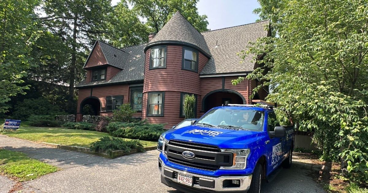 master roof truck in front of a brown house