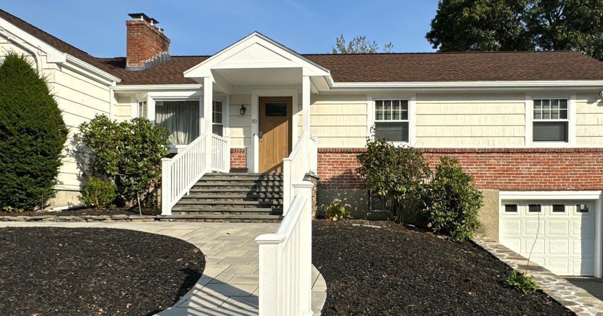 A yellow house with a brown roof in Needham, MA