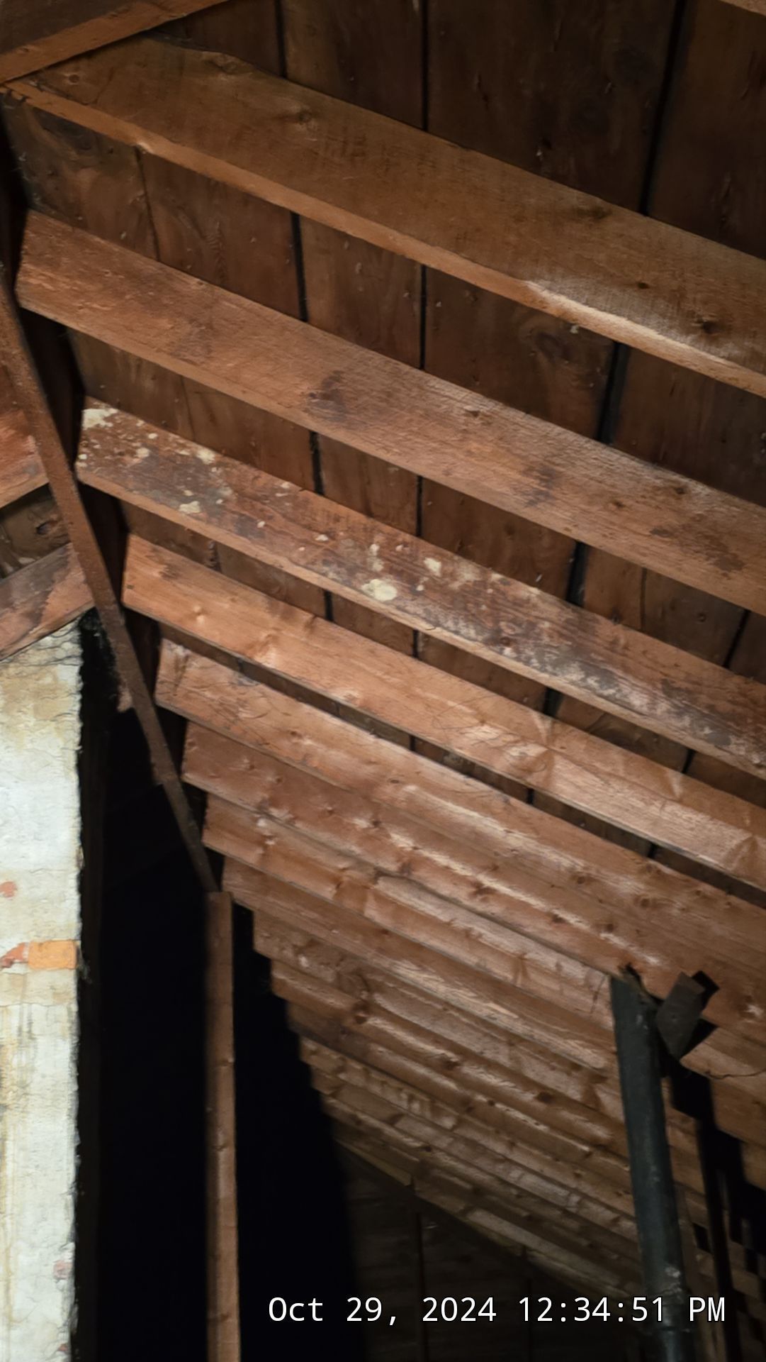 Wooden attic rafters and sheathing; dark and weathered appearance.