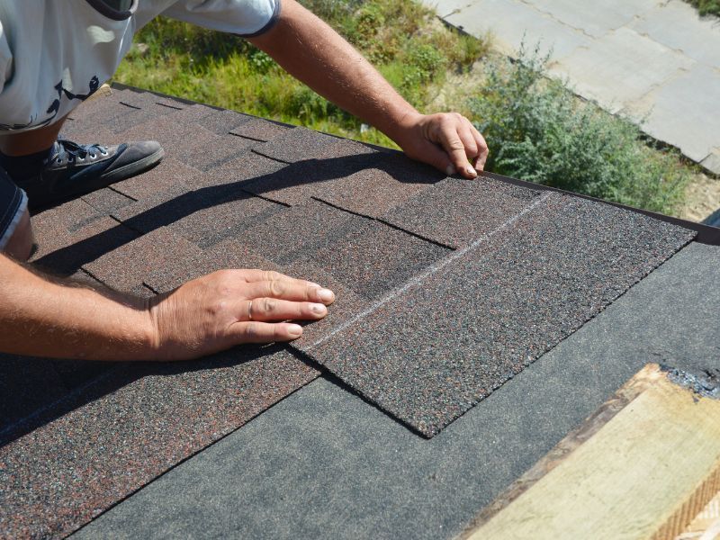 A man is installing shingles on a roof.