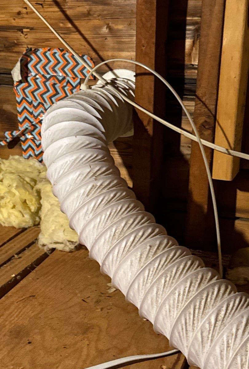 A white hose is laying on a wooden floor.