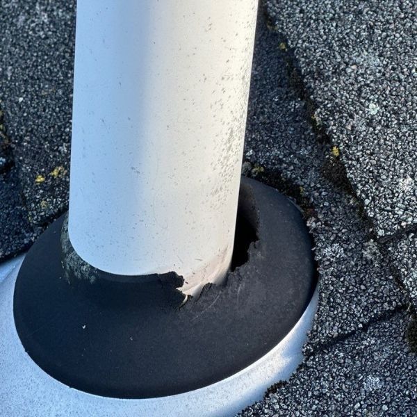 White pipe protruding from roof with damaged rubber flashing.