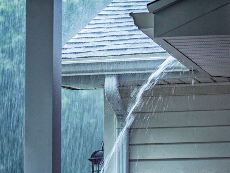 Rain is falling from the gutters of a house.
