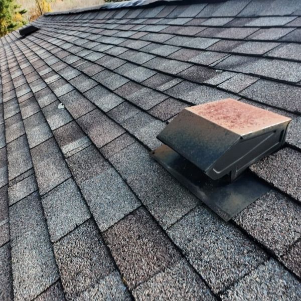 Close-up of a roof covered in asphalt shingles with a vent installed.