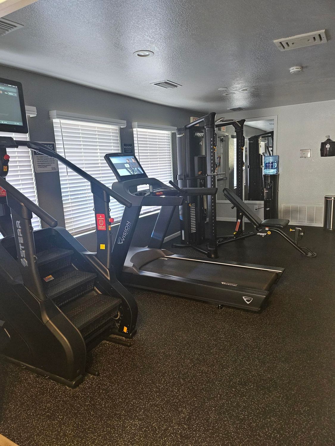 Gym with stair stepper, treadmill, and weight machines.