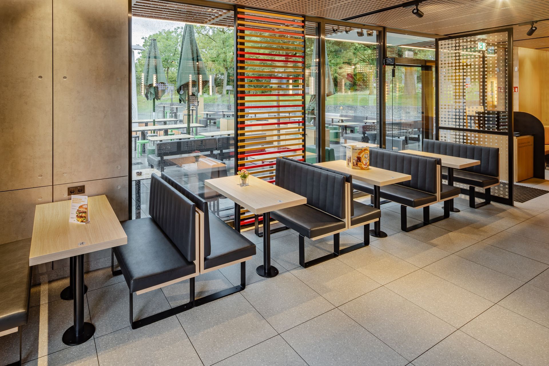 McDonald's Ray Bochum - Restaurantumbau - Schreinermöbel aus Holz, schwarze Sitzbänke und Eichen Holztische, Holztrennwände - Referenzprojekt Generalunternehmer Innenausbau