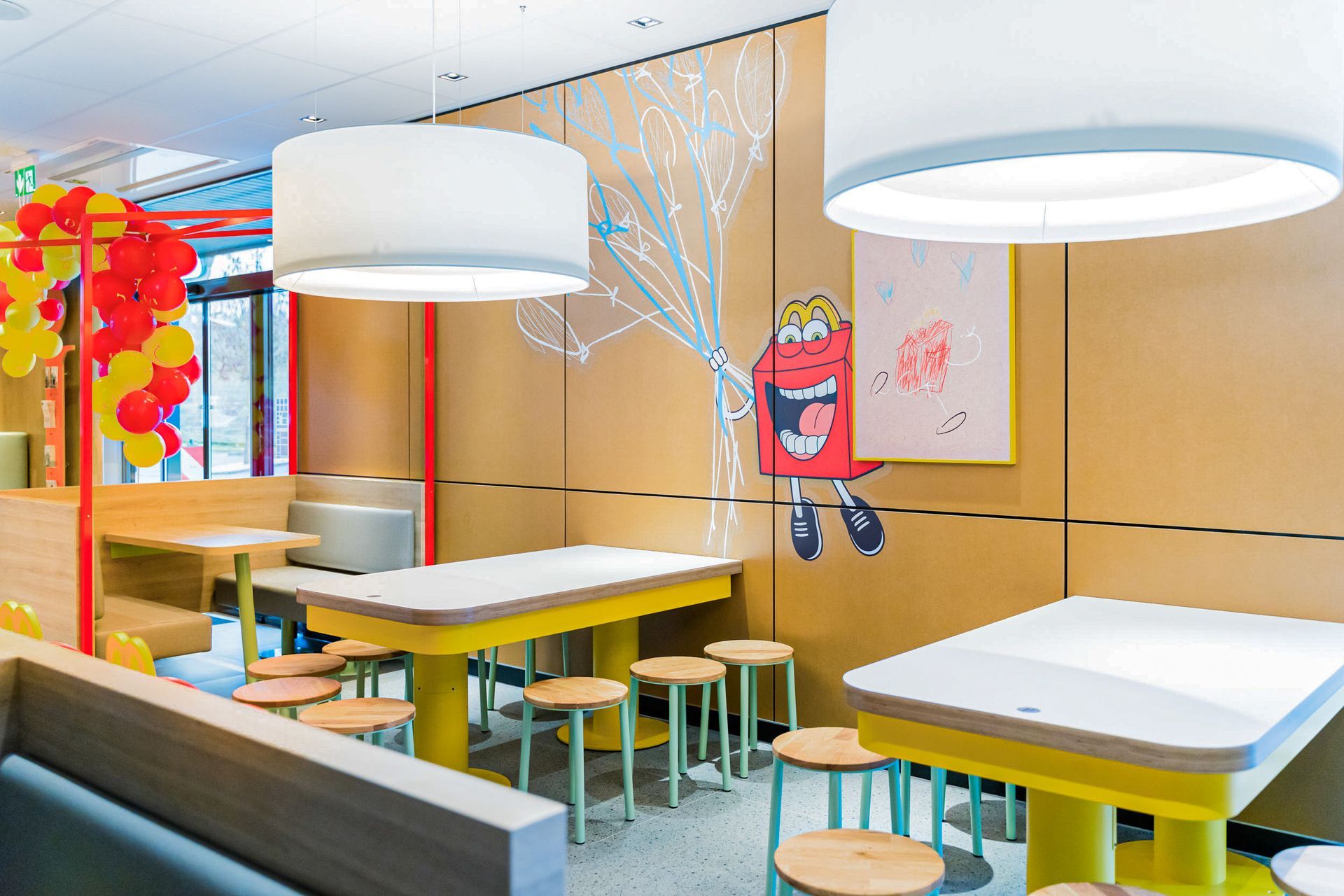 McDonald's Human Comfort Kaiserslautern - modernen Fast-Food-Restaurant, Kinderecke mit großen Holztischen und Holzhockern - Referenzprojekt Generalunternehmer Innenausbau